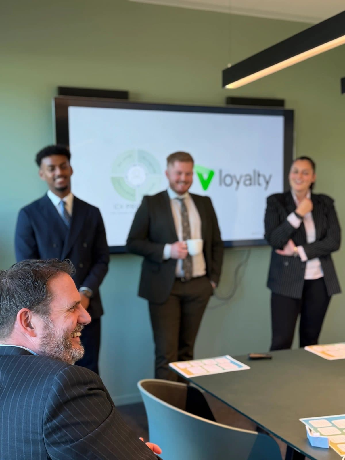 Deltakere på Loyaltys lederprogram foran en skjerm med Loyalty-logo