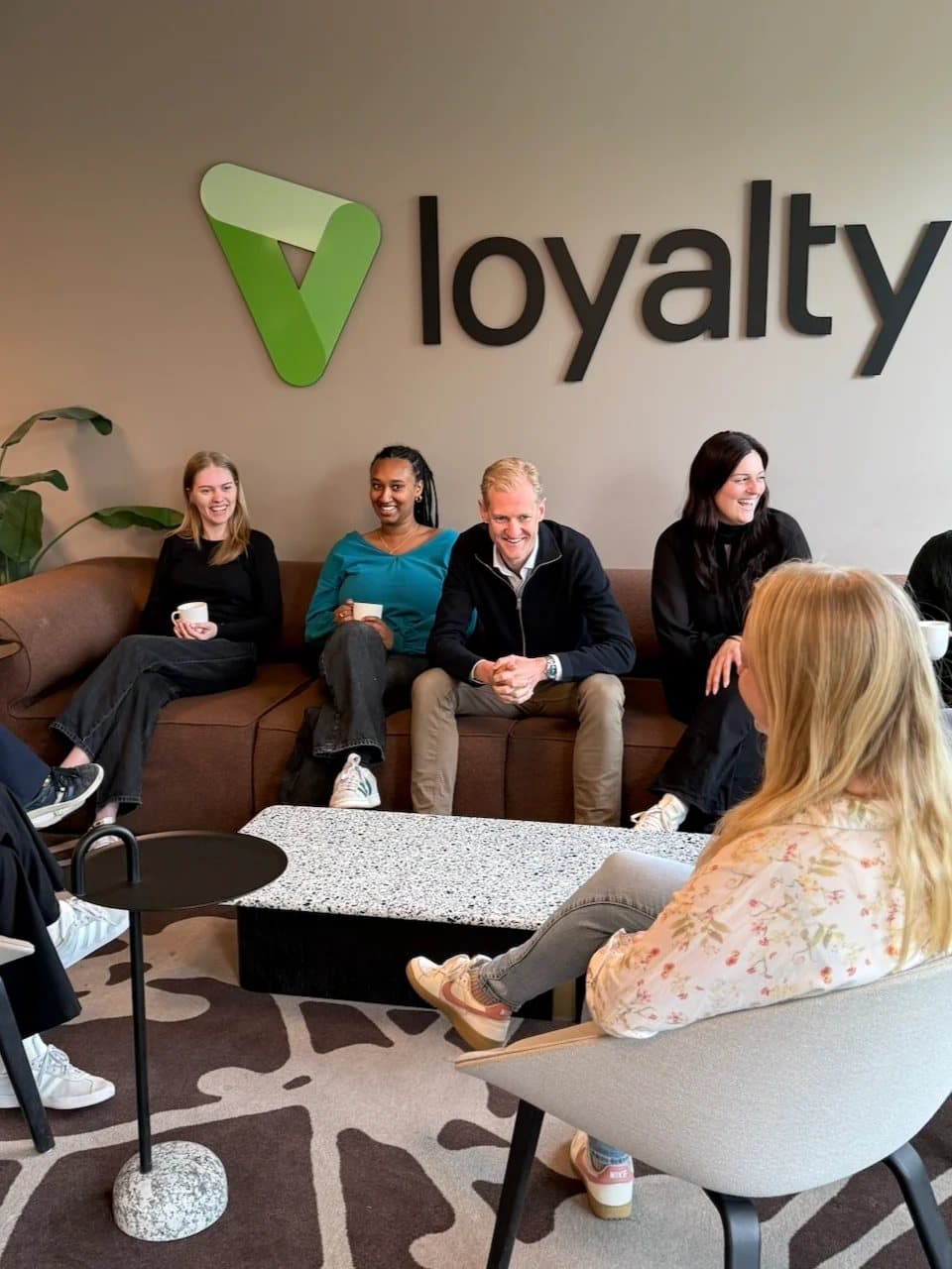 Kolleger hos Loyalty tar en pause i sofaen under Loyalty-logoen